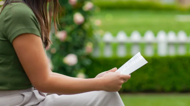 mujer sentada afuera leyendo la Biblia