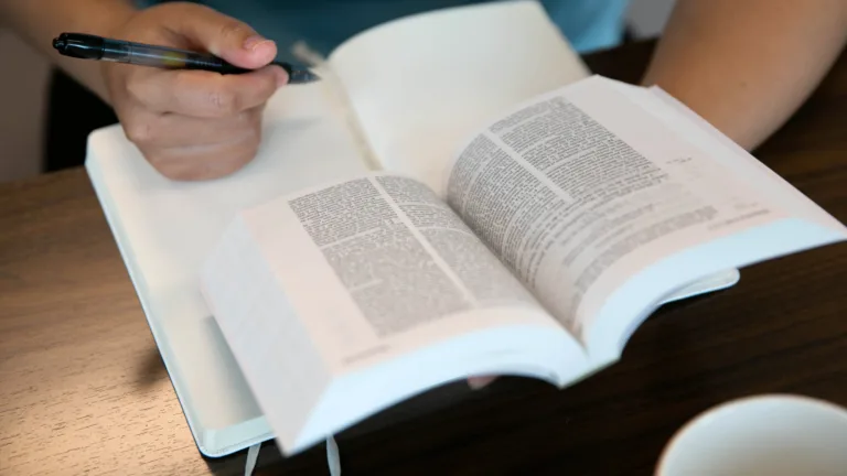 Una persona sosteniendo una Biblia abierta y un bolígrafo