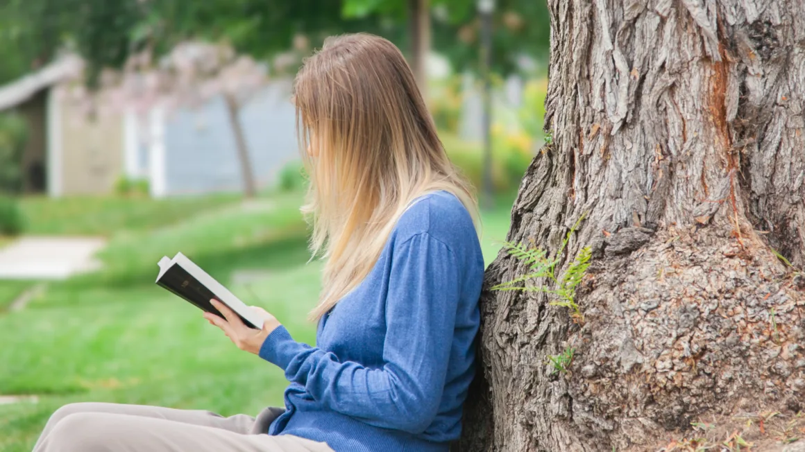 mujer sentada afuera leyendo la Biblia