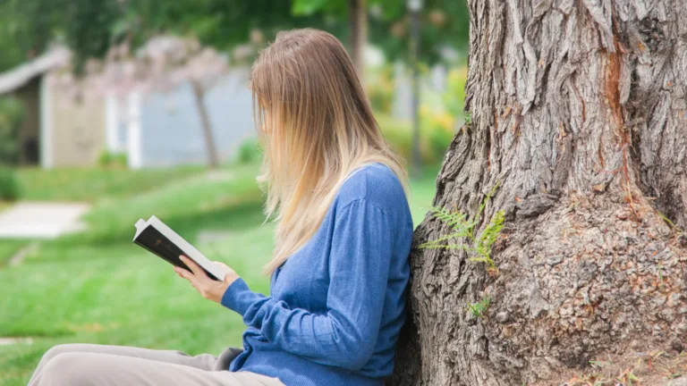 mujer sentada afuera leyendo la Biblia